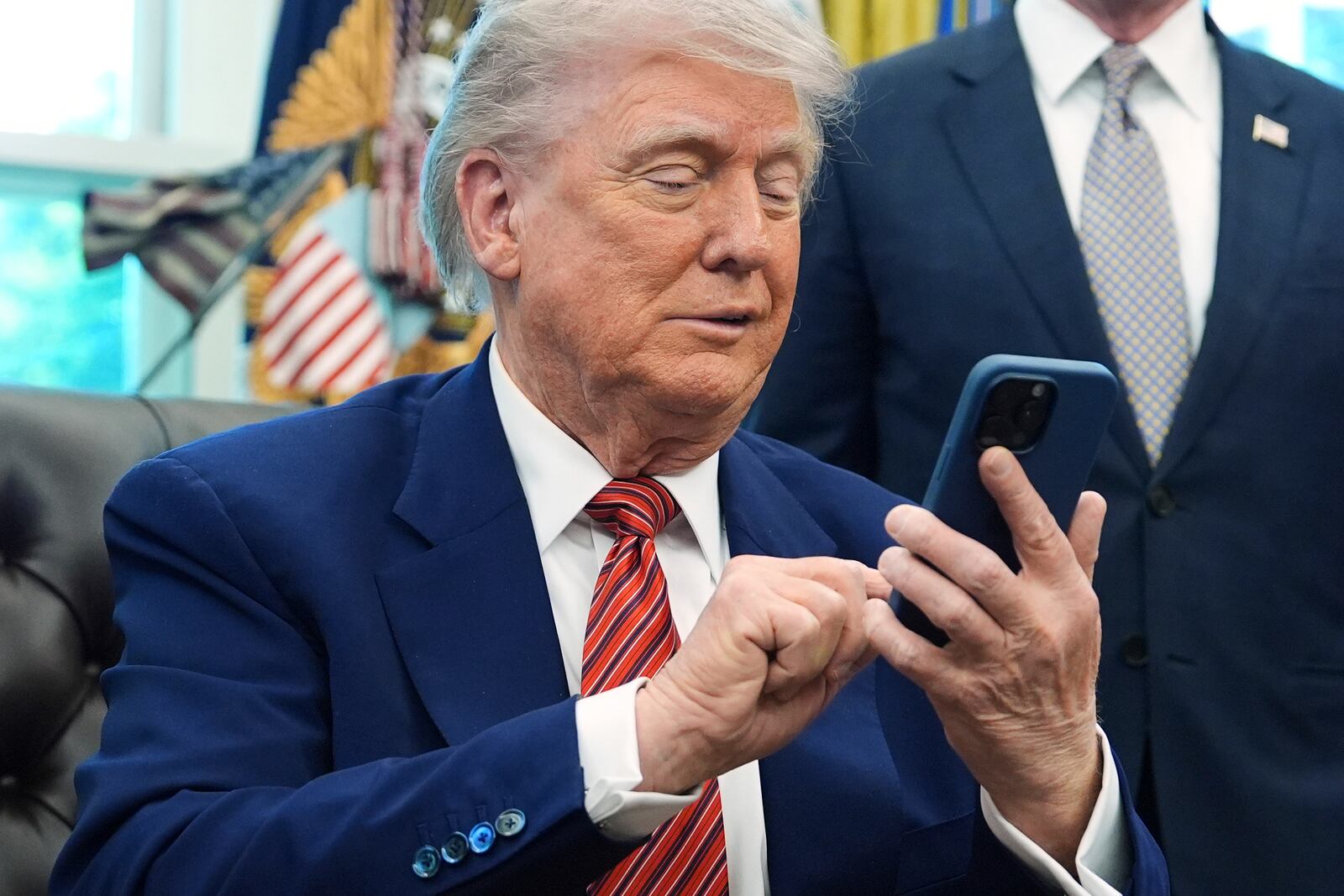 President Donald Trump silences his mobile phone which rang two times as he was speak to reporters after signing executive orders regarding nuclear energy in the Oval Office of the White House, Friday, May 23, 2025, in Washington. (AP Photo/Evan Vucci)