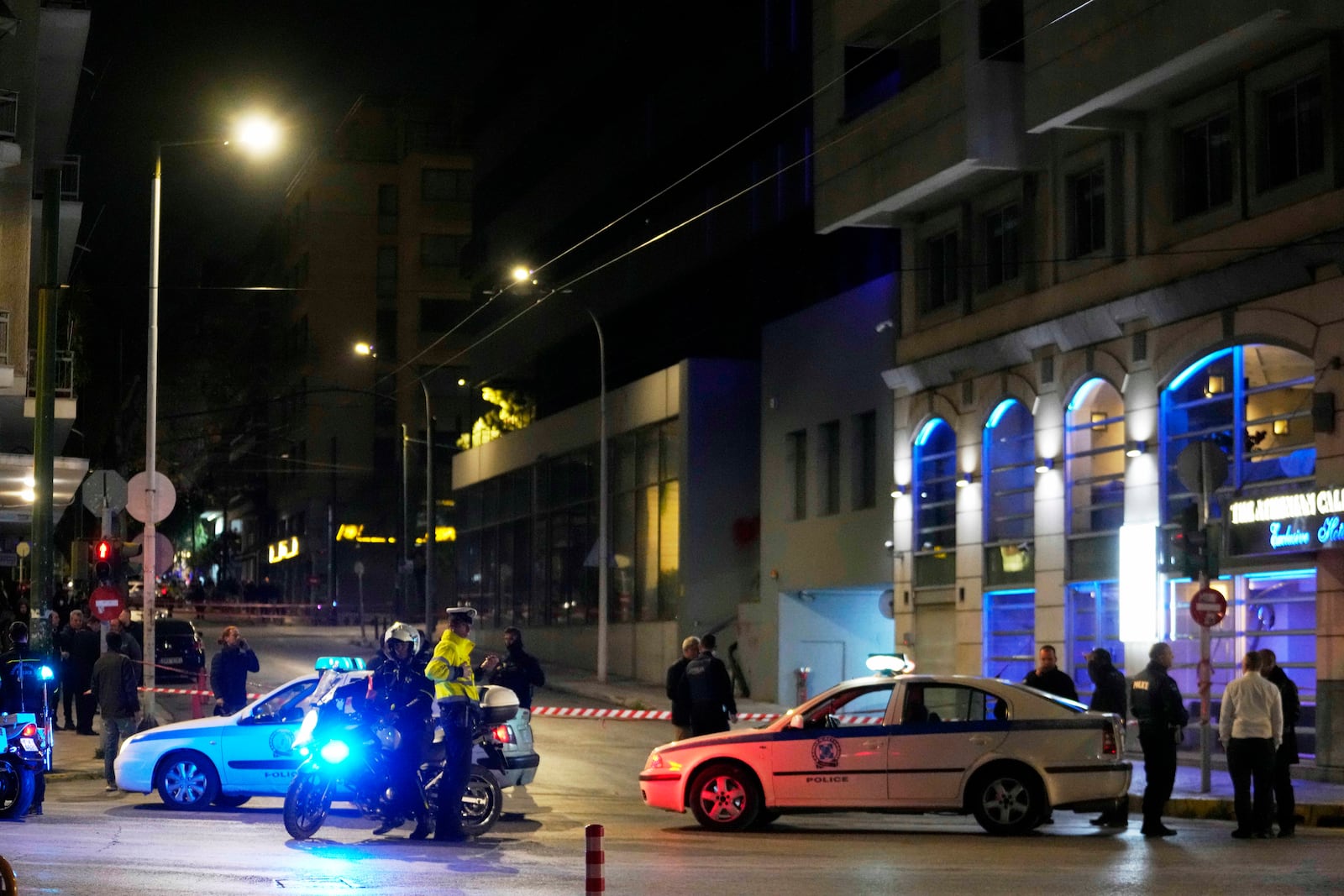 Policemen close the road after a suspected bomb explosion outside of the Hellenic Train offices the company that runs Greece's railway, the second building on the right, in Athens, Greece, Friday, April 11, 2025. (AP Photo/Petros Giannakouris)