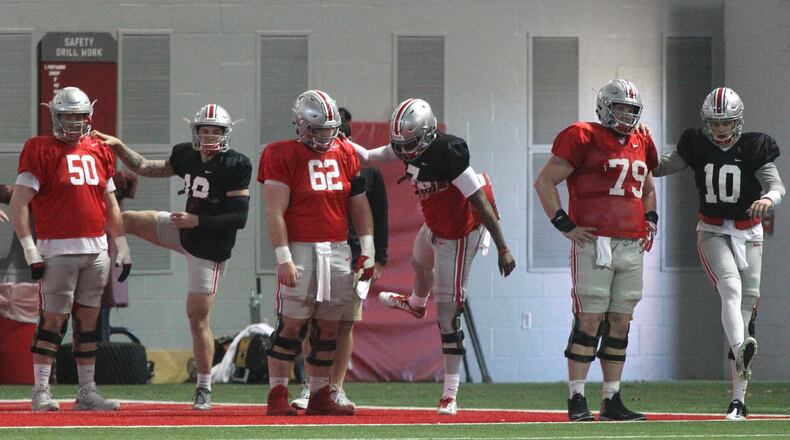 Ohio State offensive linemen and quarterbacks, including Dwayne Haskins, center in black, stretch before practice on Monday, March 26, 2018, at the Woody Hayes Athletic Center in Columbus. David Jablonski/Staff