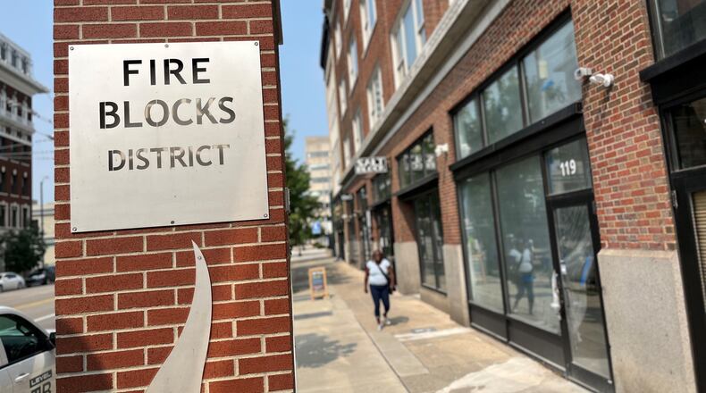 A woman walks by a storefront at 119 E. Third St. in the Fire Blocks District. The space will be home to Corporate, a new sneaker and clothing boutique that has shops in Cincinnati and Indianapolis. CORNELIUS FROLIK / STAFF
