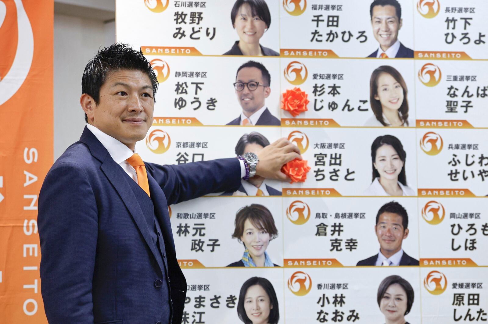 Sohei Kamiya, leader of Japan's far-right populist Sanseito party, places a red paper rose on the name of an elected candidate, in Tokyo, Sunday, July 20, 2025. (Kyodo News via AP)
