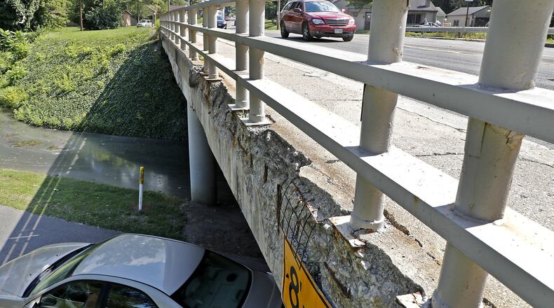 Cars drive over and under the crumbling Bechtle Avenue bridge over Snyder Park Monday. Bill Lackey/Staff