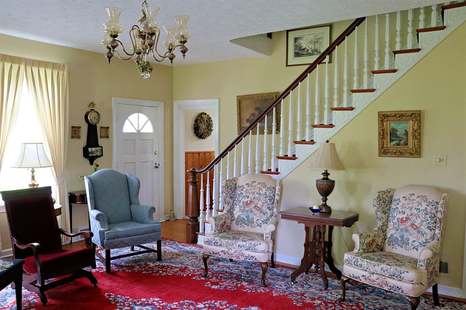The living room has hardwood flooring. Ornate woodwork accents the semi-open staircase the leads to the second floor. 