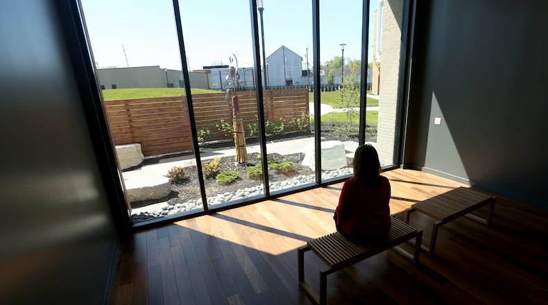 A new mixed metal and wood sculpture in the Living Reflection Garden at OneFifteen, an substance use treatment provider and recovery facility in Dayton, being viewed from an indoor reflection room. LISA POWELL / STAFF