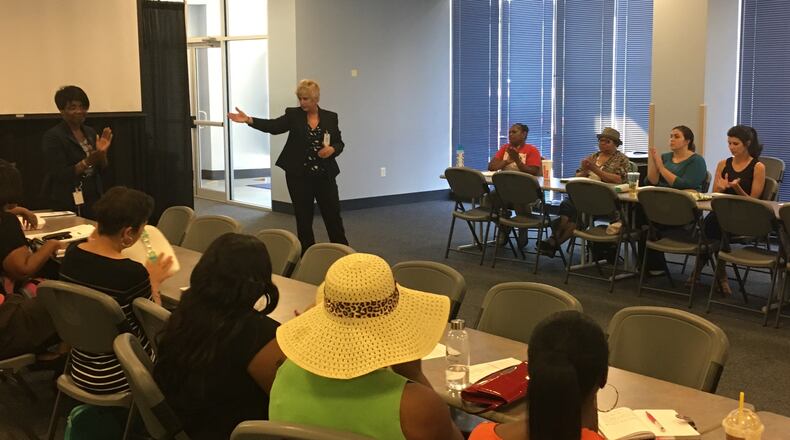 Daycare providers applaud Dayton Public Schools’ decision to provide busing service, as DPS Superintendent Rhonda Corr (center) credits Associate Superintendent Shelia Burton (left) for making the plan work. JEREMY P. KELLEY / STAFF