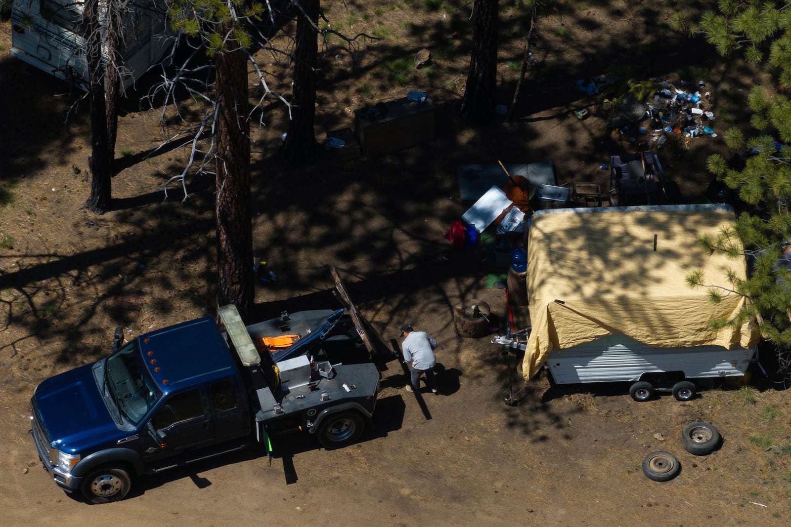 A tow truck driver helps removing a trailer for a person staying at a homeless encampment in Deschutes National Forest, Thursday, May 1, 2025, near Bend, Ore. (AP Photo/Jenny Kane)