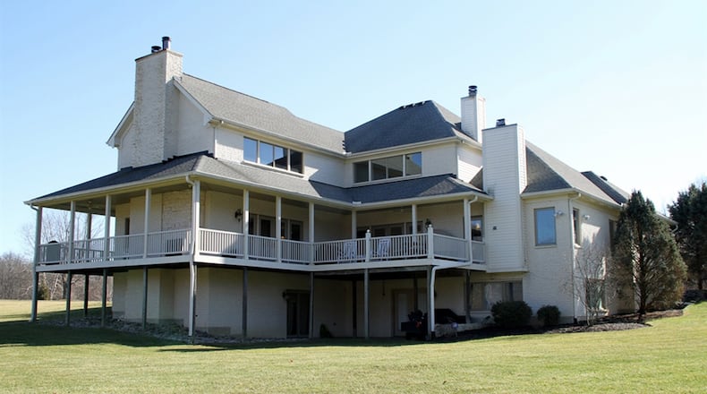 This tranquil wooded setting is enjoyed from a porch that wraps around three quarters of the home with walk-arounds to sitting areas and an outdoor gas fireplace. The 2.2-acre setting includes wide expanses of green space extending to a backdrop of thick woods at the periphery and landscaping with mostly perennials.