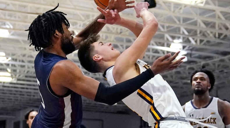 Fairleigh Dickinson forward Ansley Amonor, left, fouls Merrimack guard Jordan Derkack during the second half of Northeast Conference men's NCAA college basketball championship game, Tuesday, March 7, 2023, in North Andover, Mass. (AP Photo/Charles Krupa)