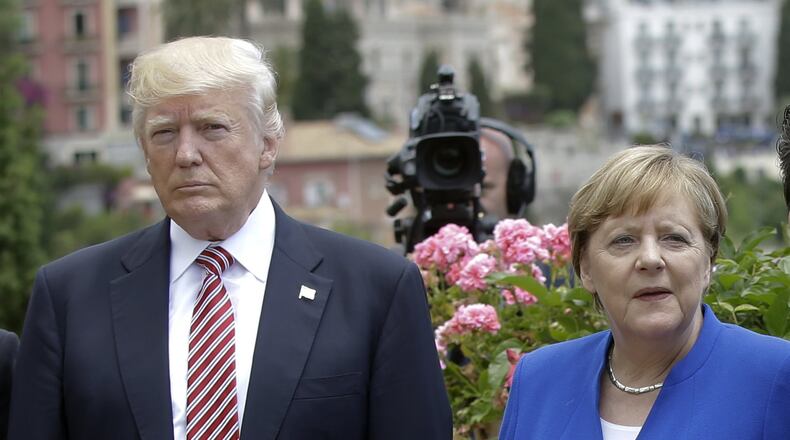 US President Donald Trump is flanked by German Chancellor Angela Merkel during the G7 meeting in Taormina, Italy, Friday, May 26, 2017. President Donald Trump keeps criticizing Germany’s trade surplus with the United States. Germans respond by saying their products are just better and people want to buy them. (AP Photo/Luca Bruno)