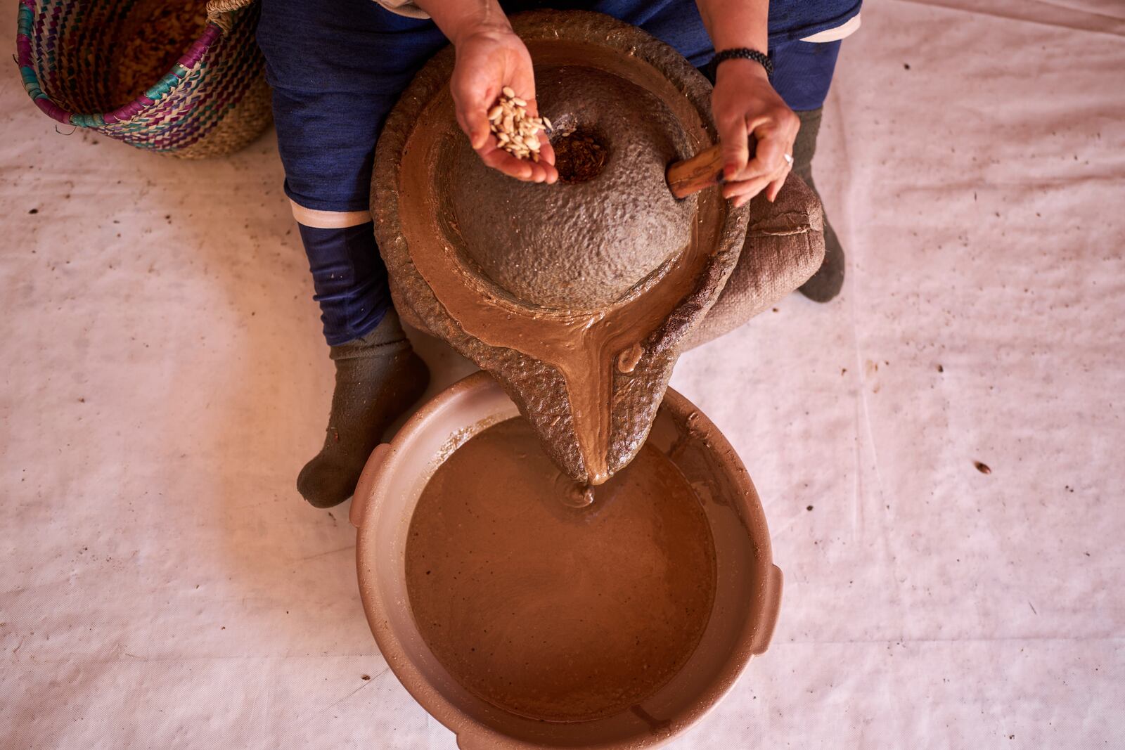 A woman pours argan nuts to extract oil at a cooperative in Essaouira, Morocco, Thursday, May 22, 2025. (AP Photo/Mosa'ab Elshamy)