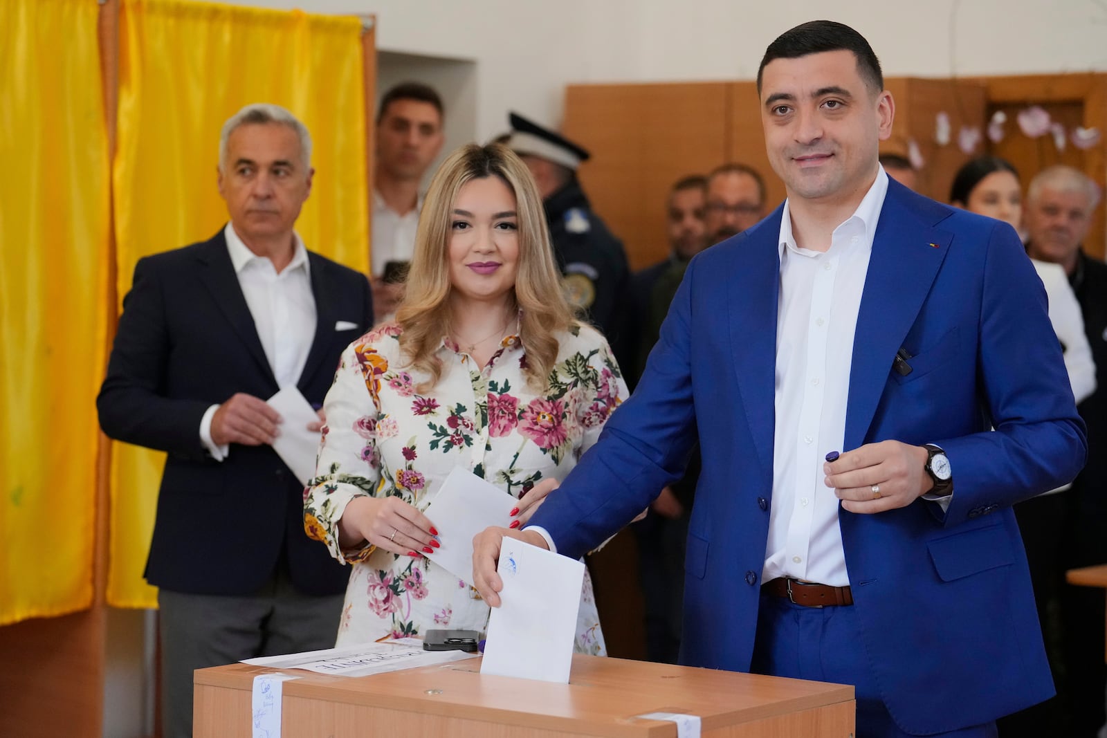 Presidential candidate George Simion casts his vote next to his wife Ilinca in the second round of the country's presidential election redo in Mogosoaia, Romania, Sunday, May 18, 2025. (AP Photo/Vadim Ghirda)