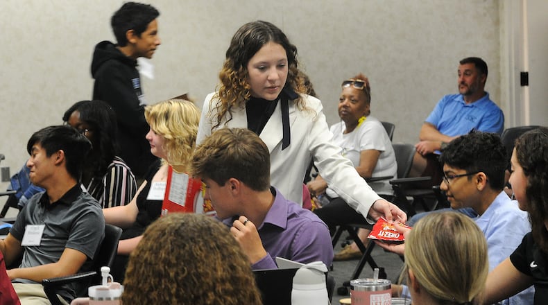 Oakwood student Charlotte Spaulding hands out packages of Cheez-It baked snack crackers to the audience Wednesday, June 12, 2024. The Cheez-It was first made in Dayton in 1921. This was part of a project presentation about why Dayton is the place to be for young professionals. Marshall Gorby / Staff