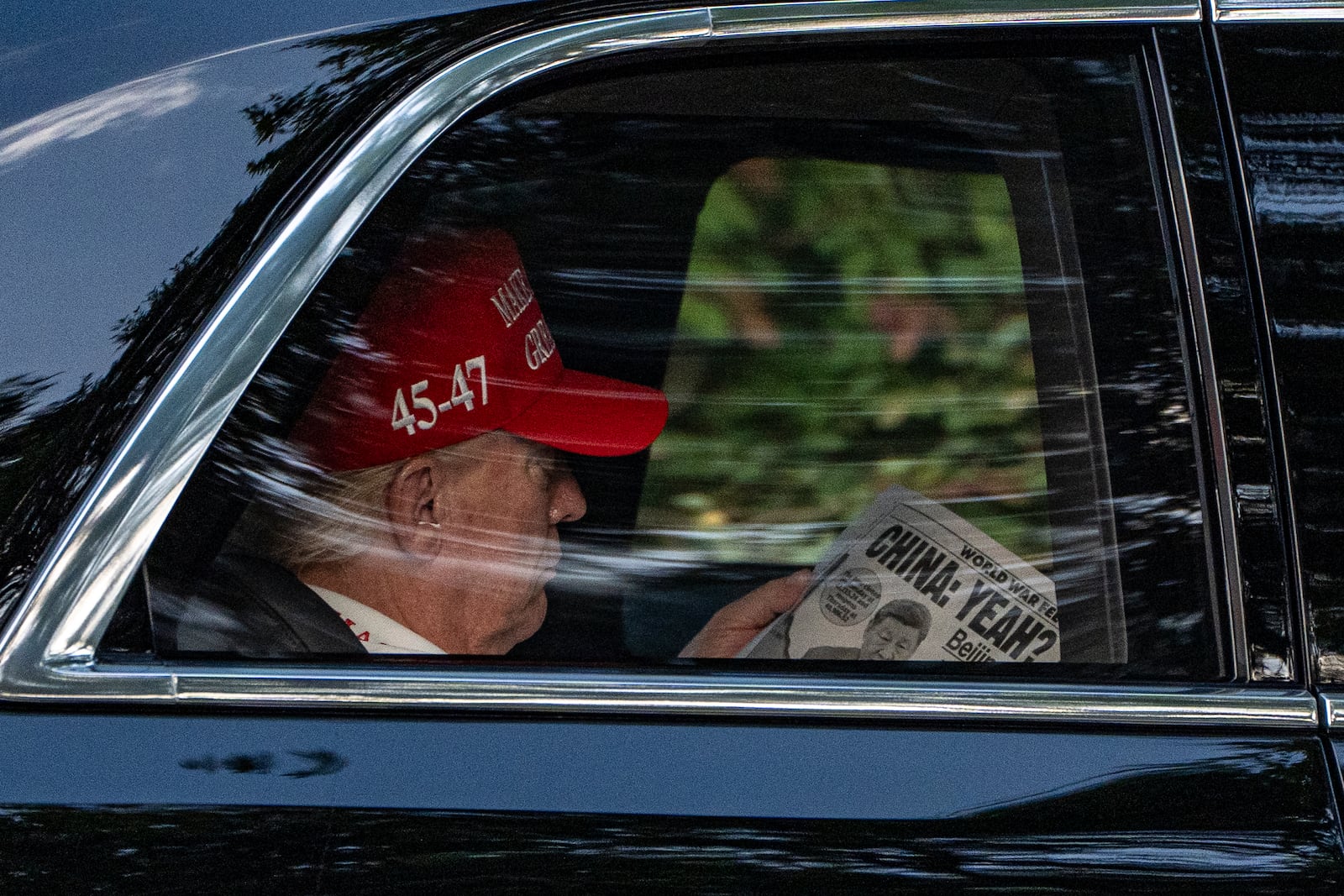 President Donald Trump reads a newspaper with the headline "World War Fee," and "China: Yeah?" as he arrives at Trump National Golf Club, Saturday, April 5, 2025, in Jupiter, Fla. (AP Photo/Alex Brandon)