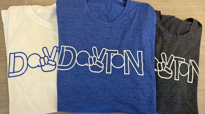 Just in time for the NATO Parliamentary Assembly, the Downtown Dayton Partnership is debuting t-shirts highlighting Dayton’s newest landmark. The shirts (available in royal blue, charcoal or white) feature the design of the new Dayton Peace Sign, currently located at RiverScape MetroPark (FACEBOOK PHOTO).