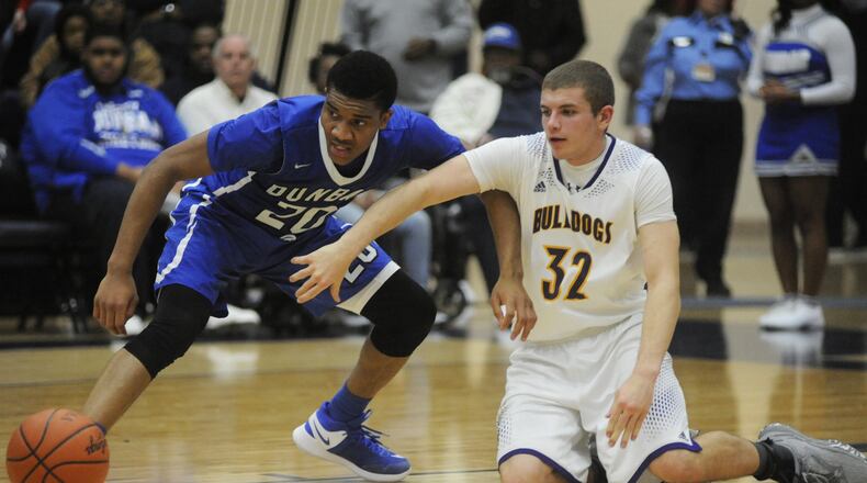 Dunbar’s Devon Baker (left) battles Jared Laski for a loose ball. Dunbar defeated Carroll Bloom-Carroll 71-37 in a boys high school basketball D-II regional final at Fairmont’s Trent Arena on Thursday, March 16, 2017. MARC PENDLETON / STAFF