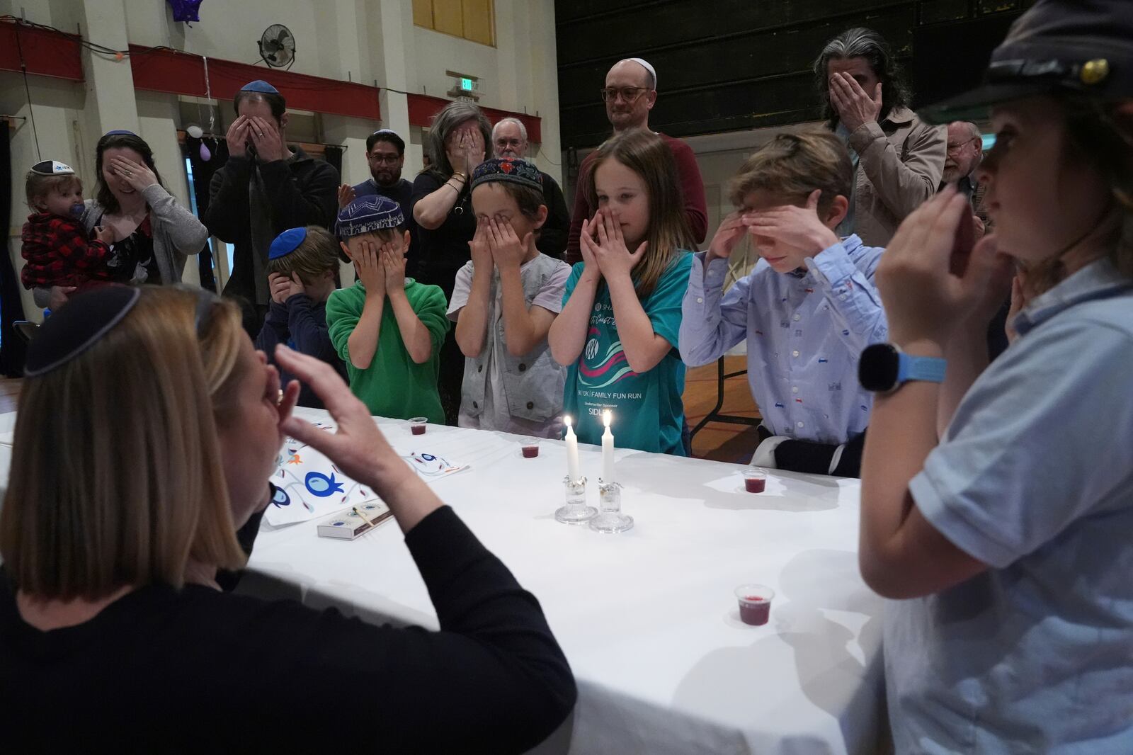 Cantor Ruth Berman Harris, left, who leads the congregation in lieu of a full-time rabbi, lights candles to celebrate Seder with congregants of the 104-year-old Pasadena Jewish Temple and Center which burned down in the Jan. 2025 Eaton fire, gathered for a Passover at the First United Methodist Church in Pasadena, Calif. on Friday, April 4, 2025. (AP Photo/Damian Dovarganes)