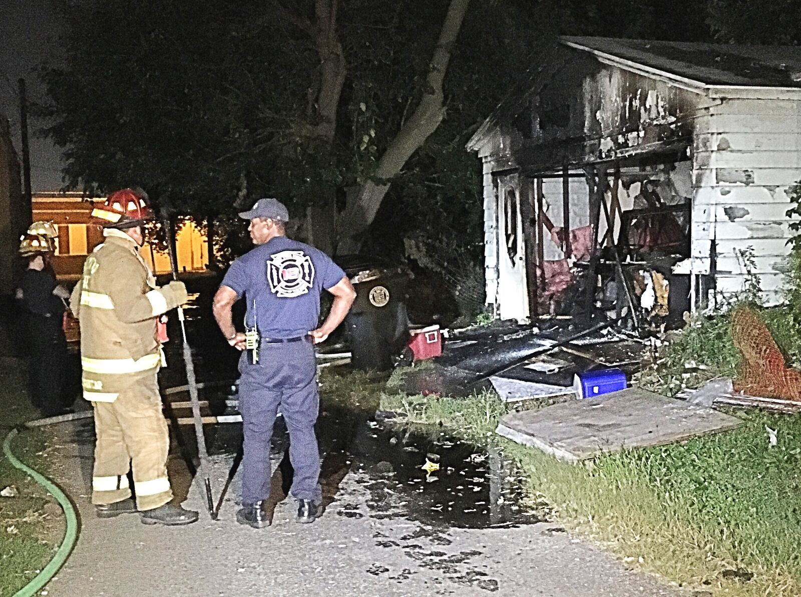 Firefighters investigate a fire that broke out in a garage behind a home on North Horton Street in Dayton Monday. Police and fire crews responded to the scene Tuesday after a body was reportedly found inside the garage. (Marshall Gorby/Staff)