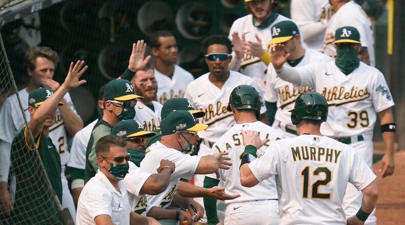 Oakland Athletics' Sean Murphy (12) and Tommy La Stella, second from lower right, are congratulated by teammates after both scored against the Chicago White Sox during the fifth inning of Game 3 of an American League wild-card baseball series Thursday, Oct. 1, 2020, in Oakland, Calif. (AP Photo/Eric Risberg)
