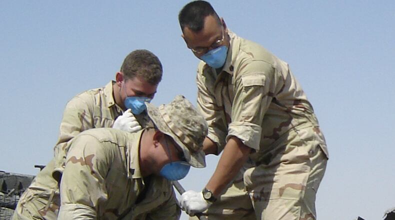 Chris Bussler (standing) in Iraq, as his unit breaks down a melted M2A2 Bradley fighting vehicle. CONTRIBUTED