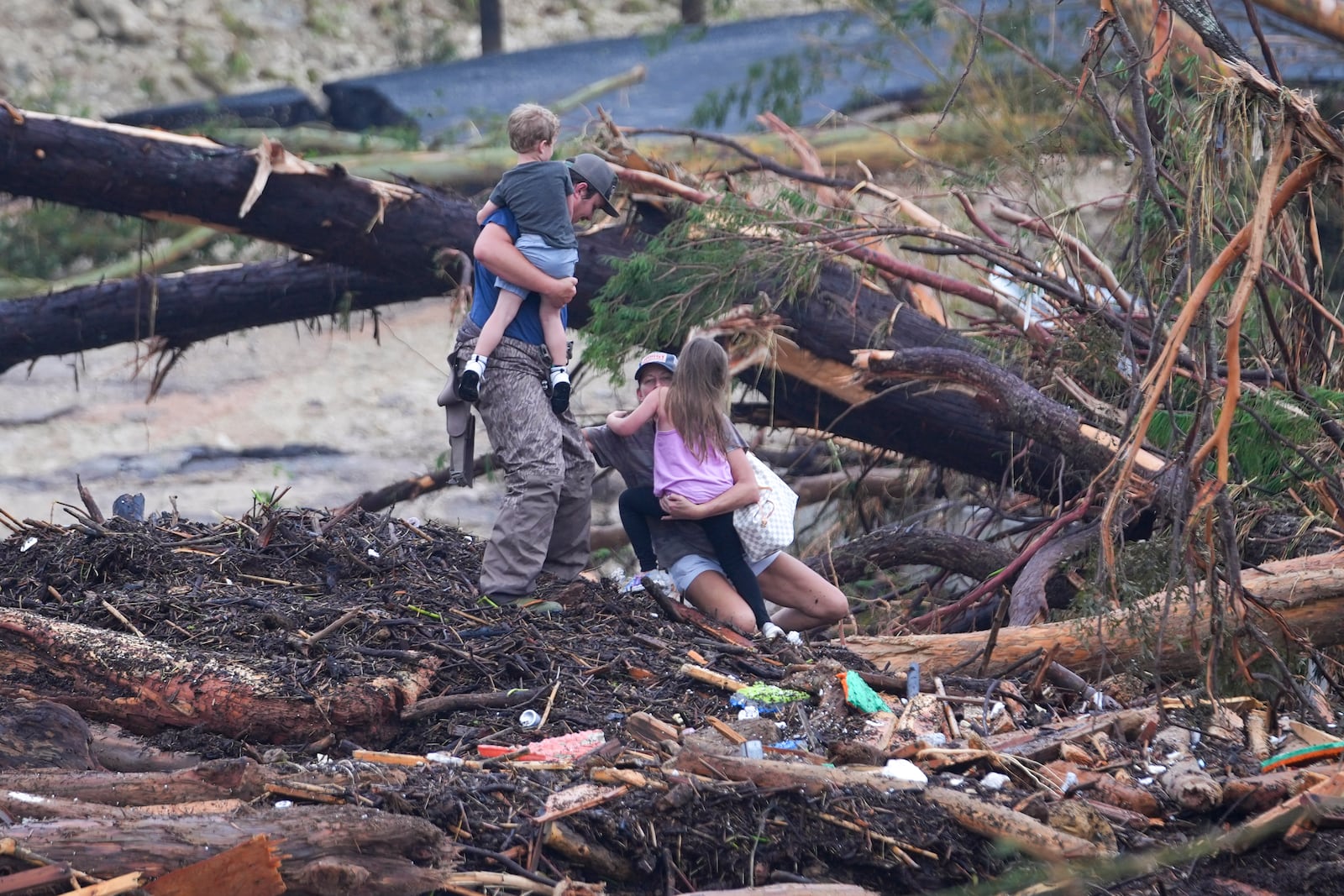 A woman falls while climbing with others over debris on a bridge atop the Guadalupe River after a flash flood swept through the area Saturday, July 5, 2025, in Ingram, Texas. (AP Photo/Julio Cortez)