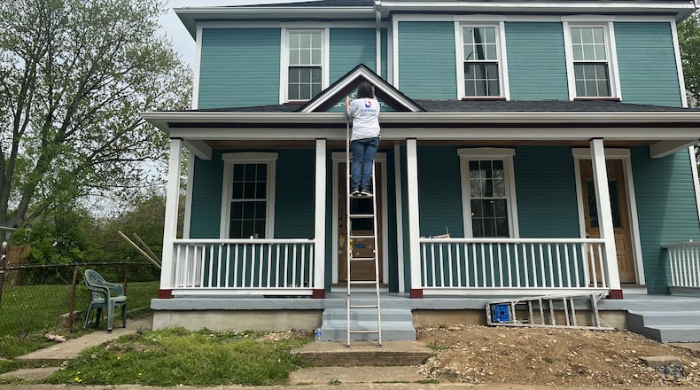 A woman works on the exterior of a home in the St. Anne's Hill neighborhood. CORNELIUS FROLIK / STAFF
