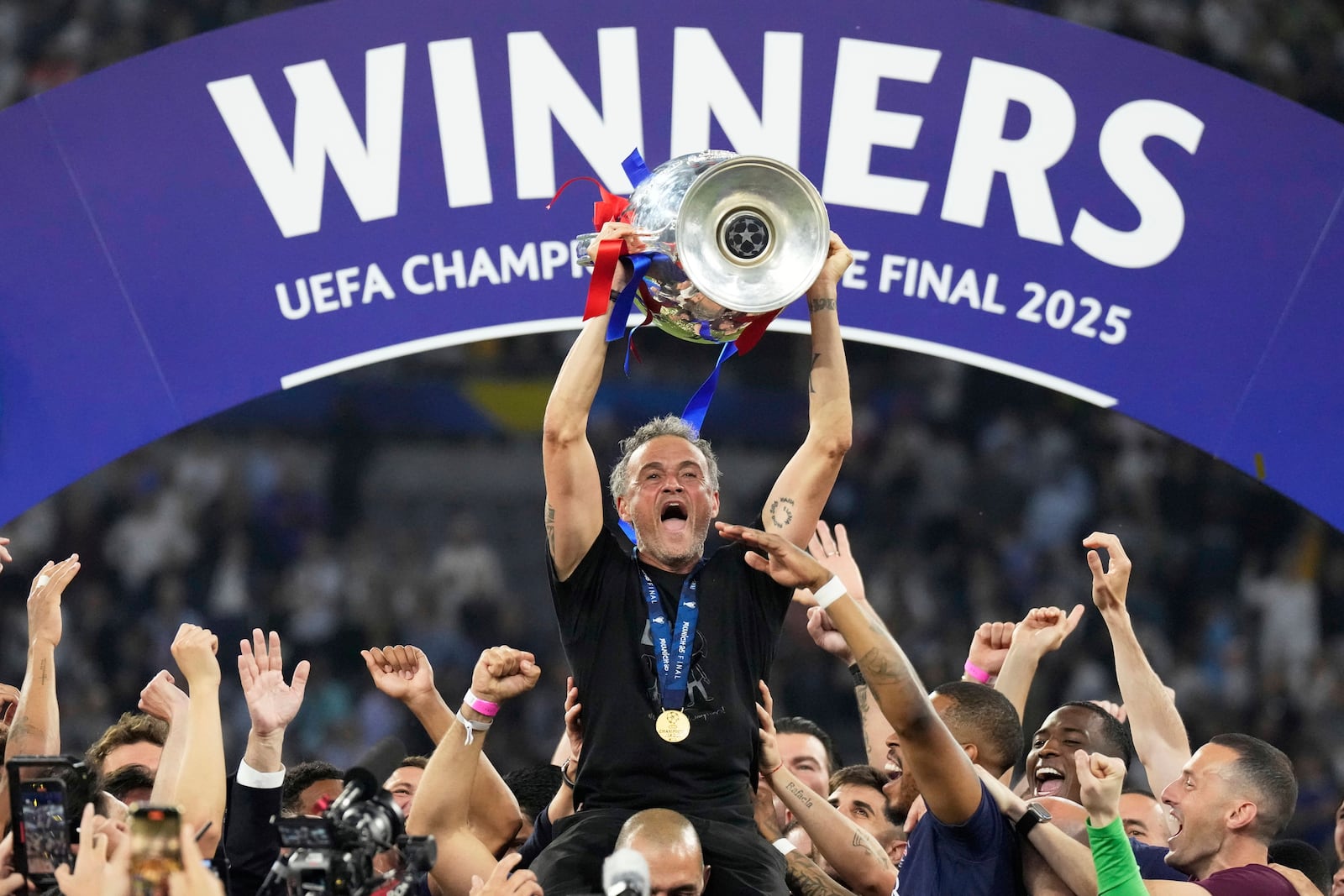 PSG's head coach Luis Enrique celebrates with the trophy after the Champions League final soccer match between Paris Saint-Germain and Inter Milan at the Allianz Arena in Munich, Germany, Saturday, May 31, 2025. (AP Photo/Matthias Schrader)