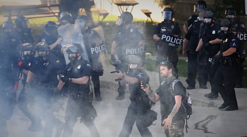 Dayton police deploy tear gas to disperse a crowd of protesters in July 2020 after some began to riot, damaging police cruisers and businesses in the city. MARSHALL GORBY / STAFF