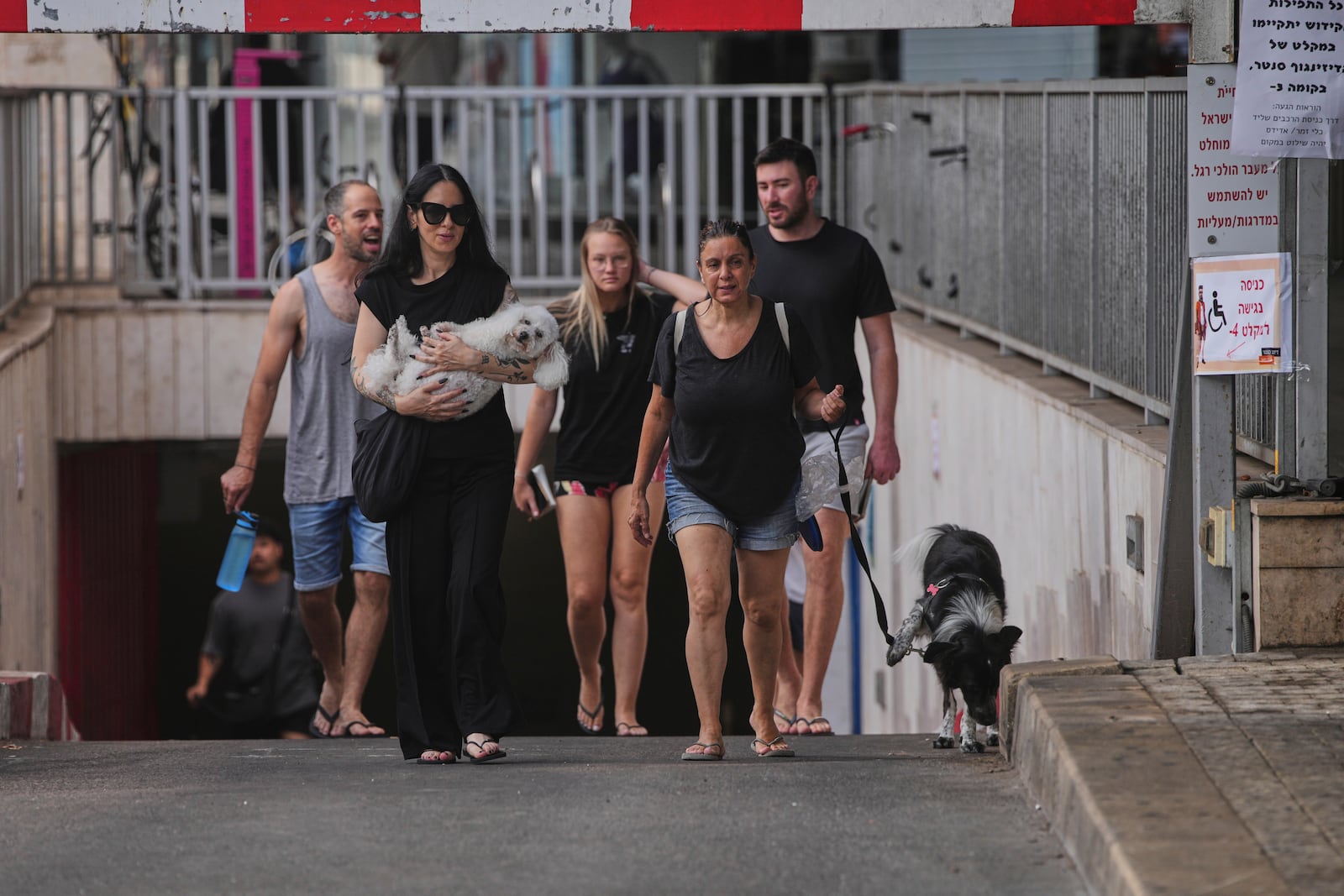 People leave an underground parking garage where they took shelter after an air raid alarm of Iranian missile attacks went off, in Tel Aviv, Israel, Tuesday, June 24, 2025. (AP Photo/Ohad Zwigenberg)