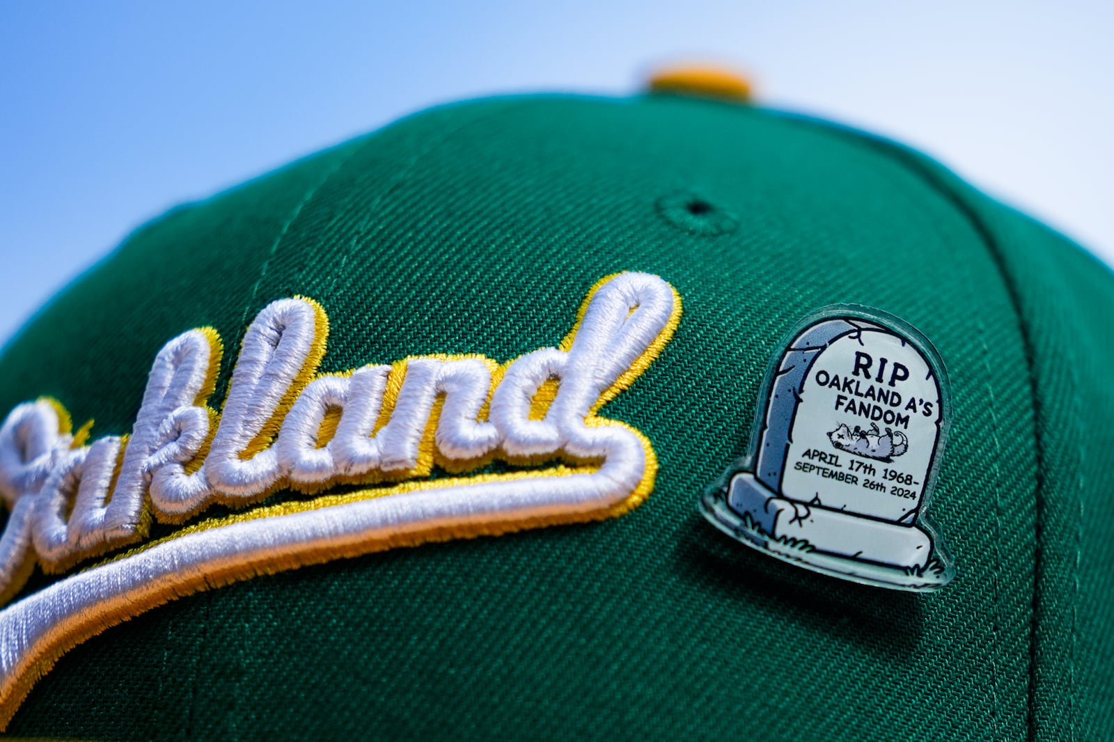 FILE - A fan wears an Oakland Athletics hat with a pin referencing the end of the team's time in Oakland before a baseball game against the Seattle Mariners, Sunday, Sept. 29, 2024, in Seattle. (AP Photo/Lindsey Wasson, File)