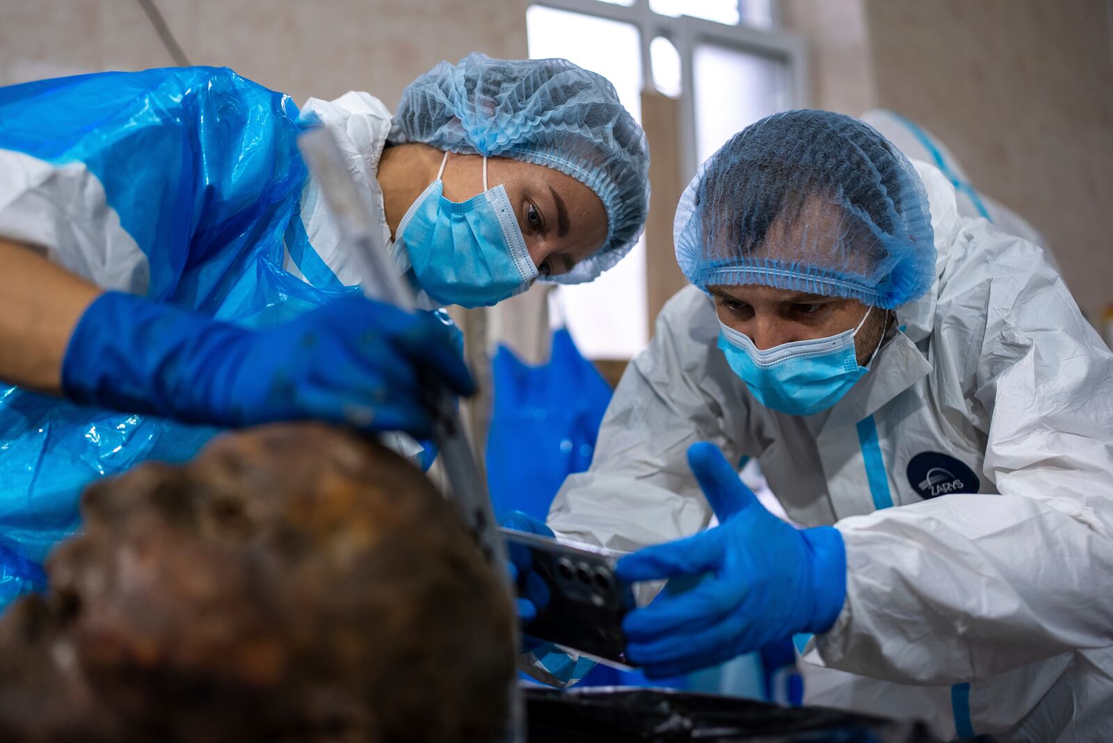 Forensic workers at a morgue in Kyiv, Ukraine, examine the body of a Ukrainian prisoner of war returned by Russia, June 24, 2024. (AP Photo/Alex Babenko)