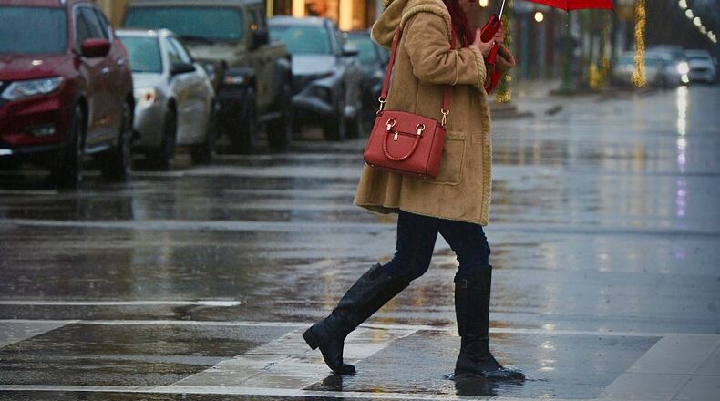 Rain and snow seems to be the recipe for the day, Tuesday, January 9, 2023 as this lady, uses an umbrella to do her shopping at the Greene Town Center. MARSHALL GORBY \STAFF
