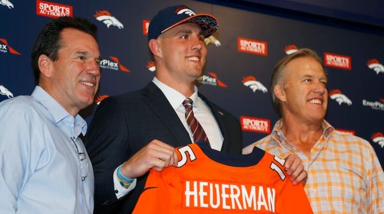 FILE - In this May 2, 2015, file photo, former Ohio State tight end Jeff Heuerman, center, the Denver Broncos third-round pick in the NFL Draft, holds up his new jersey while posing for a photograph with head coach Gary Kubiak, left, and general manager John Elway during a news conference in Englewood, Colo. The Broncos are among several teams that have changed the way they handle rookie minicamps in the two years since two prized picks sustained season-ending knee injuries less than a week after all the hugs and handshakes of draft night. Locker rooms, fan bases and front offices alike were jolted when defensive end Dante Fowler, the third overall pick in 2015, blew out his left knee on the first day of Jacksonville's rookie minicamp. Twenty-four hours later, Heuerman tore his left ACL covering a kickoff. (AP Photo/David Zalubowski, File)