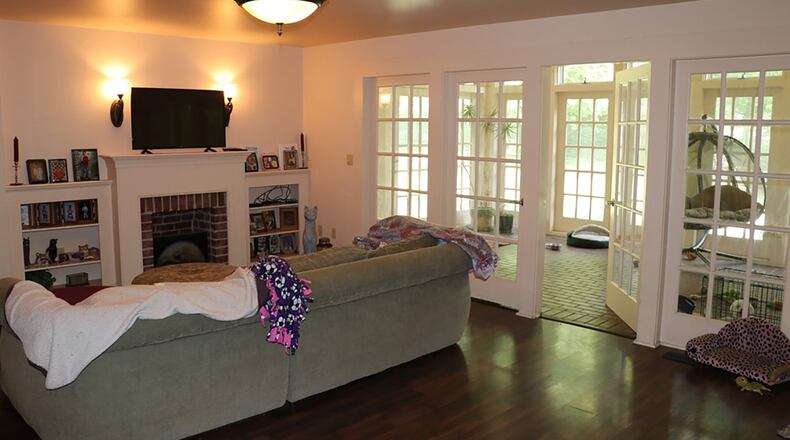 On the opposite side of the kitchen a wide opening leads into the family room, where the fireplace and brick hearth are flanked with bookshelves. The adjacent sun porch, surrounded with tall rectangular windows, connects to the brick-edged patio.