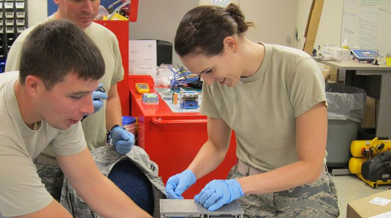 1st Lt. Ayesha (right) and Capt. Joshua insert a machine screw into an Air Force Institute of Technology satellite payload mass model. The Airmen will continue to perform vibrational testing to ensure the AFIT payload structure will meet NASA rocket launch specifications. (U.S. Air Force photo/Chris Sheffield)