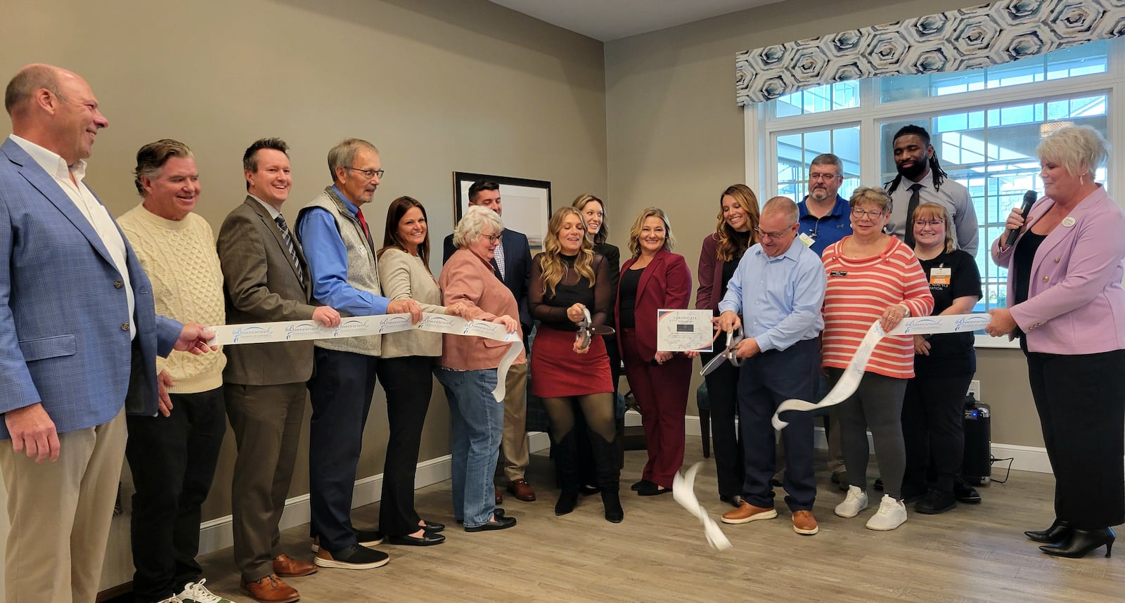 Administrator Sam Clark (center), surrounded by staff and local dignitaries, cuts the ribbon marking the grand opening of Overbrook Landing, a new skilled nursing facility in Beavercreek Twp. LONDON BISHOP/STAFF