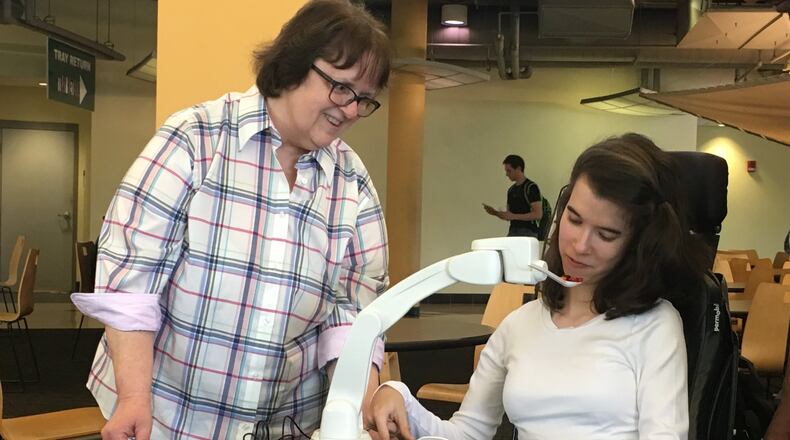 Sarah Faith Davis is a freshman at Wright State University and has needed help being fed at mealtimes. Now she won’t need someone to feed her thanks to locally developed and manufactured Obi feeders, which use a robotic arm to scoop and move food toward the users mouth. STAFF PHOTO / HOLLY SHIVELY
