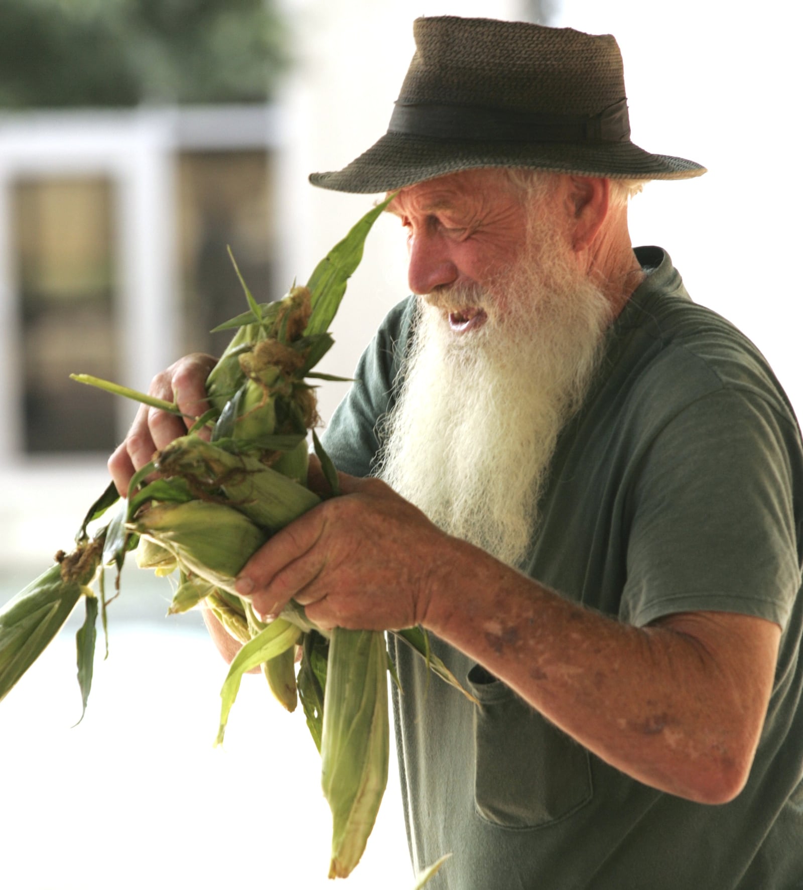 Russell Garber stacks sweetcorn ears as he talks with a customer on the first day of the Wegerzyn Gardens MetroPark Farmer's Market on Courthouse Square, 2006.  Photo by Jim Witmer
