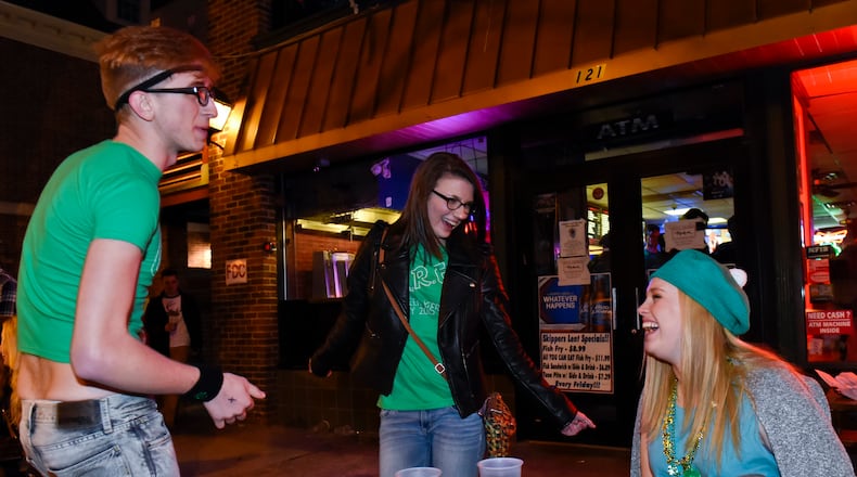 Jacob Rasmussen and Megan Kudej dance as Sidney Calicoat watches as they sit in front of Skippers before sunrise during Green Beer Day Thursday, March 19 in Oxford. NICK GRAHAM/ STAFF