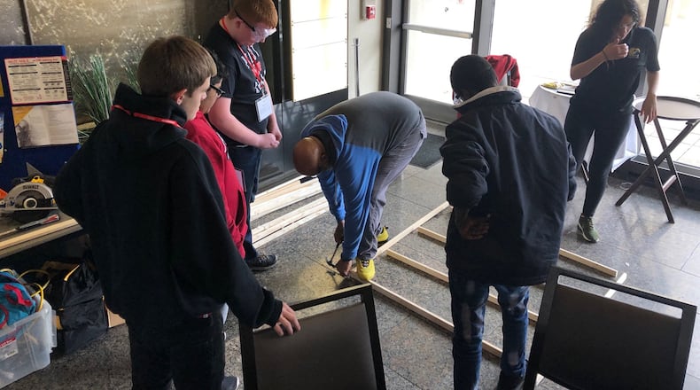Keith Beason (center), who teaches construction classes at Dayton’s Ponitz Career Tech Center, demonstrates carpentry framing skills to eighth-graders at a Dayton Public Schools career exploration event Tuesday, Jan. 21, 2020, at Sinclair Community College. JEREMY P. KELLEY / STAFF