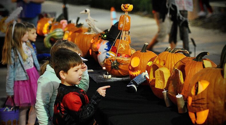 Children look over the pumpkins in the pumpkin carving contest Saturday during the New Carlisle Halloween Night Market. Marshall Gorby/Staff