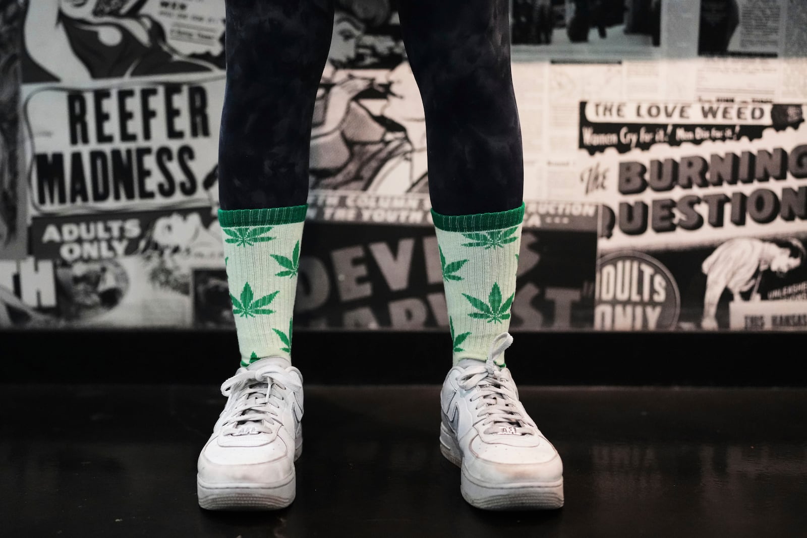 A customer at Have a Heart cannabis dispensary poses for a photo while wearing marijuana-themed leaf socks Sunday, April 20, 2025, in Seattle. (AP Photo/Lindsey Wasson)
