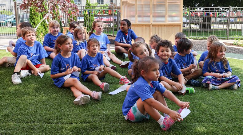 Children at Rainbow Years Child Care sit on a small hill after a ceremony for an outdoor playground and learning lab at the center on South Smithville Road in Dayton on Wednesday, June 25. The new playground was constructed with funds from the PNC Foundation. BRYANT BILLING / STAFF