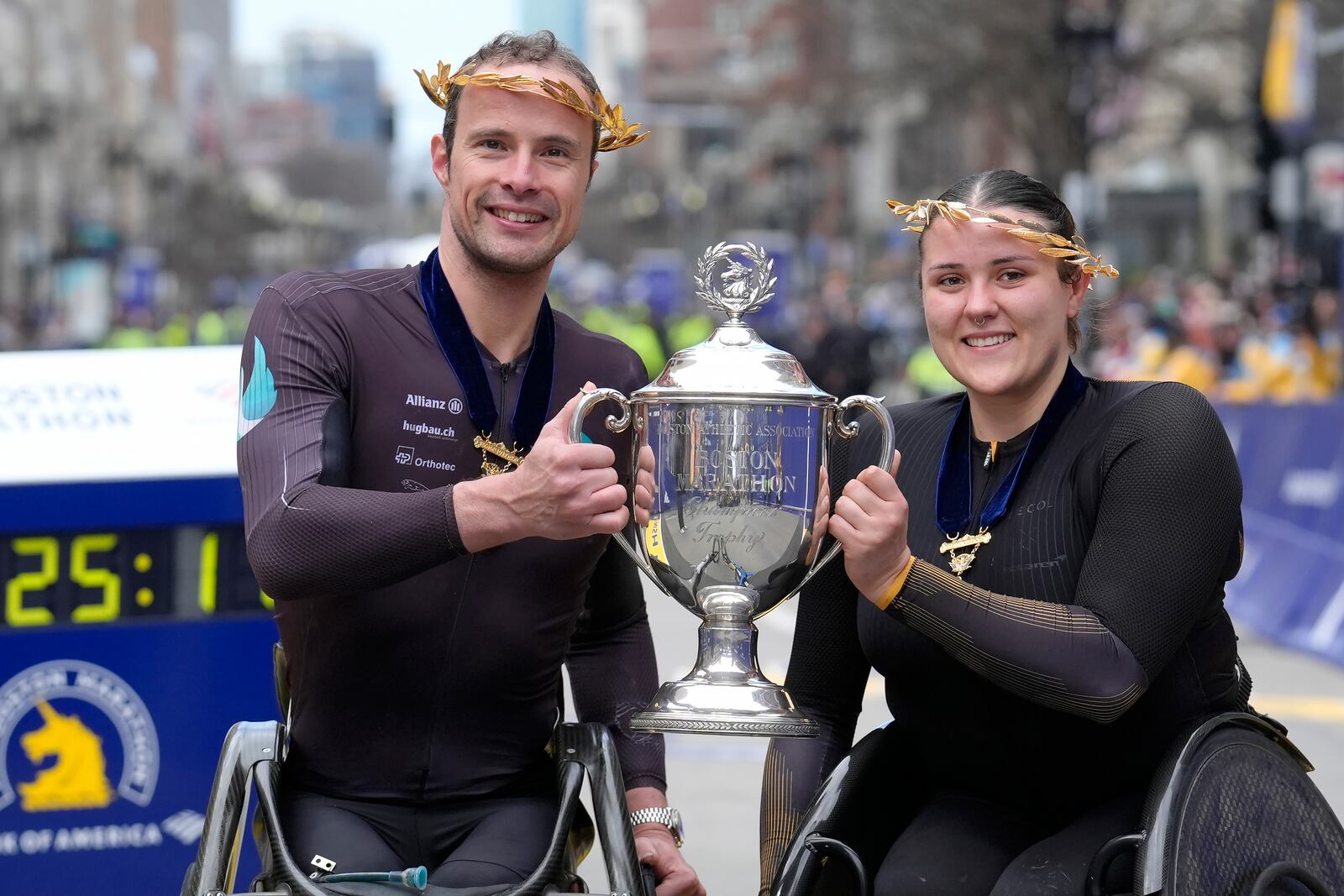 FILE - Marcel Hug, of Switzerland, left, winner of the Boston Marathon men's wheelchair division, and Eden Rainbow Cooper, of Britain, right, winner of the women's wheelchair division, display the trophy on the finish line of the Boston Marathon, Monday, April 15, 2024, in Boston. (AP Photo/Steven Senne, File)