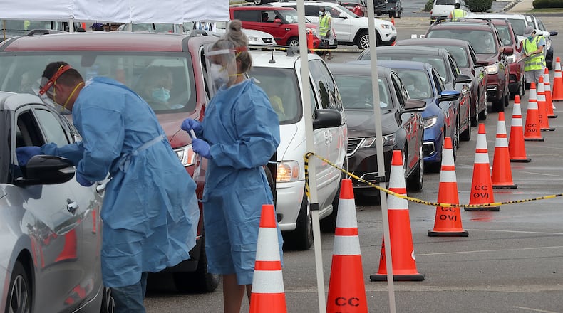 People wait in their cars for a free COVID-19 test in the Burnett Plaza parking lot. BILL LACKEY/STAFF
