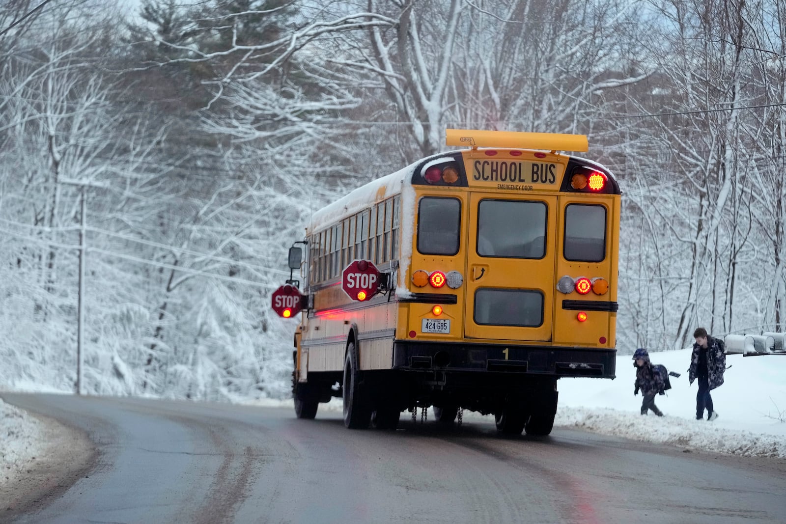 FILE - Children are picked up by their school bus following a day off due to a winter storm, Wednesday, March 15, 2023, in Poland, Maine. (AP Photo/Robert F. Bukaty, File)