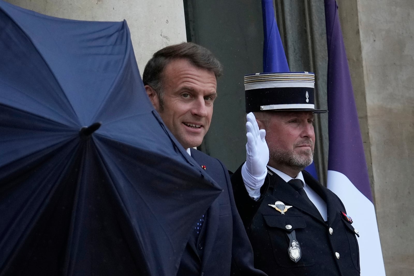 French President Emmanuel Macron uses an umbrella as he waits for Lebanese Prime Minister Nawaf Salam Thursday, July 24, 2025 at the Elysee Palace in Paris. (AP Photo/Michel Euler)