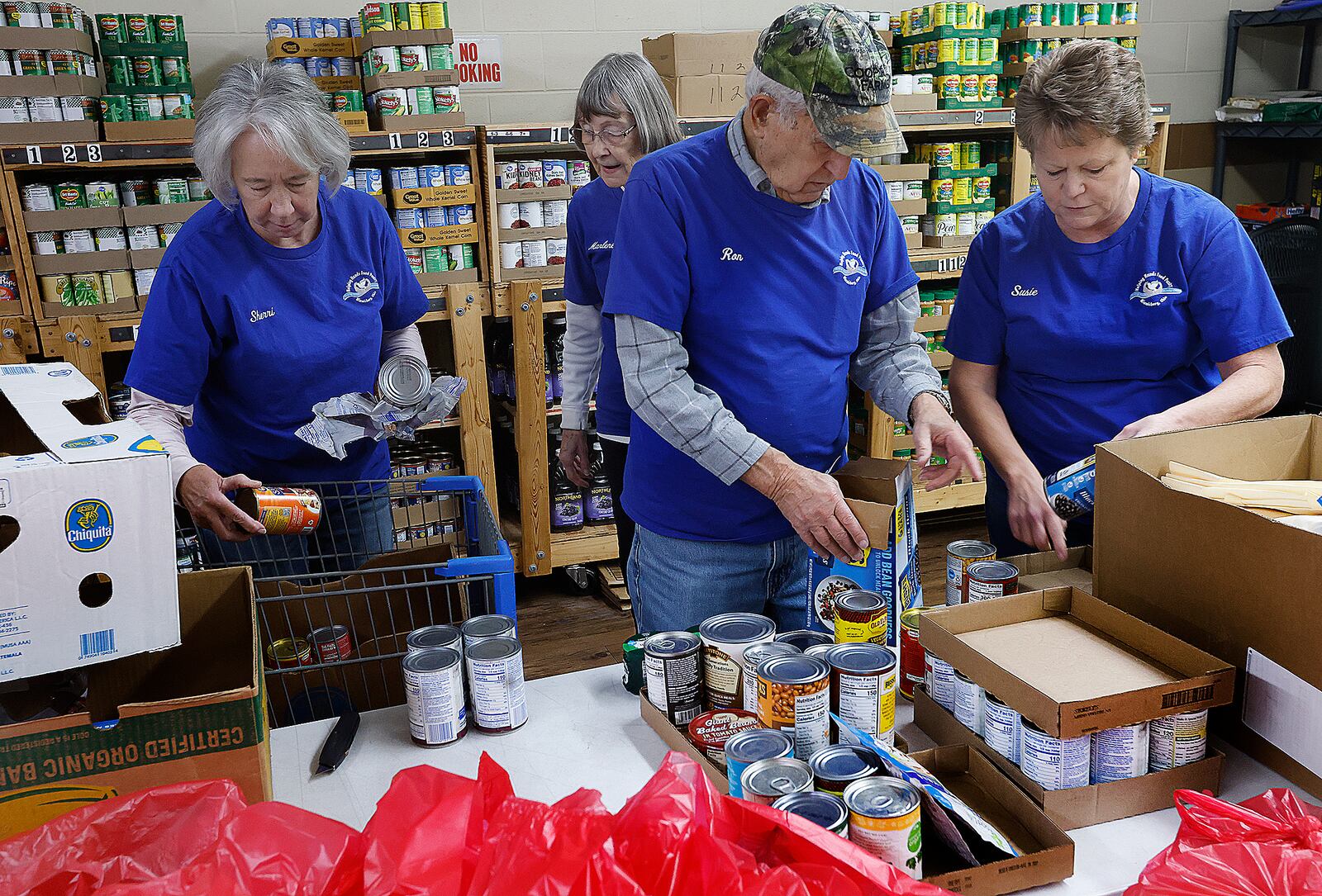 Miamisburg Helping Hands Food Pantry volunteers, from left, Sherrie Iddings, Marlene Schmitz, Ron Schmitz and Susie Huffman sort cans of food, Wednesday, Feb. 12, 2025. The nonprofit organization got its start on Feb. 17, 1965. MARSHALL GORBY/STAFF
