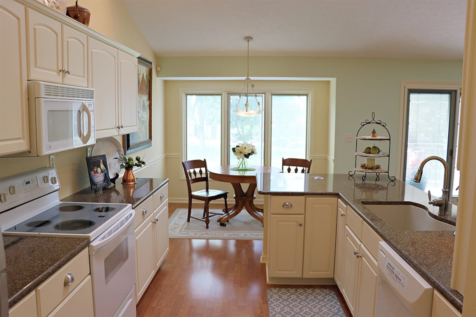 The breakfast room is an extension of the kitchen, which has white cabinetry and dark quartz counters.