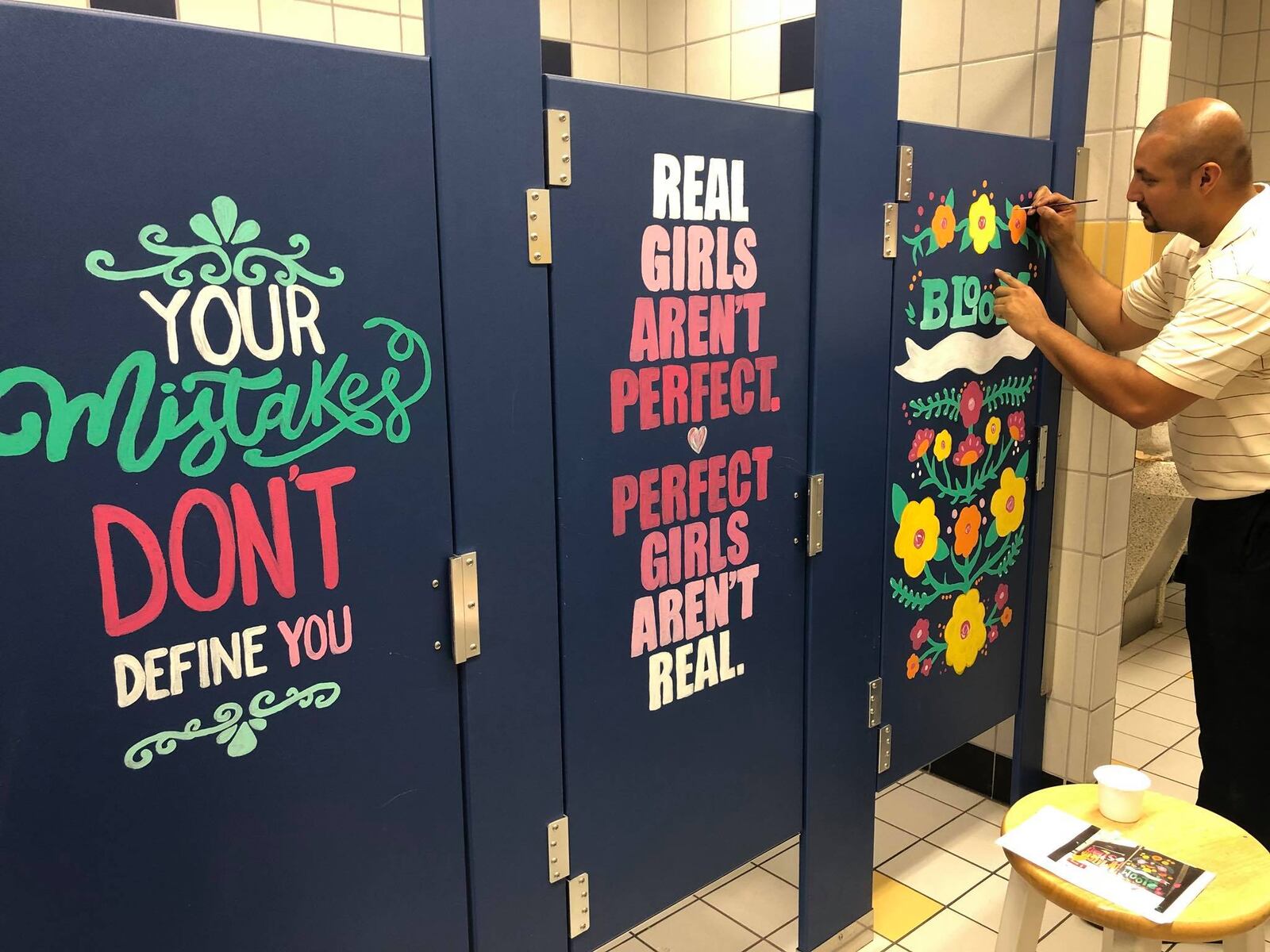 Principal adds finishing touches to one of the bathroom stalls.
