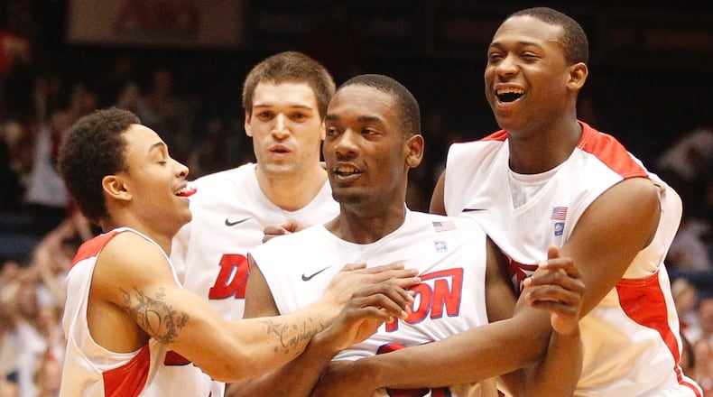 Dayton's Dyshawn Pierre, center, is congratulated by Kyle Davis, left, Alex Gavrilovic, back, and Kendall Pollard after hitting a 3-pointer at the buzzer to end the first half against Rhode Island on Wednesday, Feb. 12, 2014, at UD Arena. David Jablonski/Staff